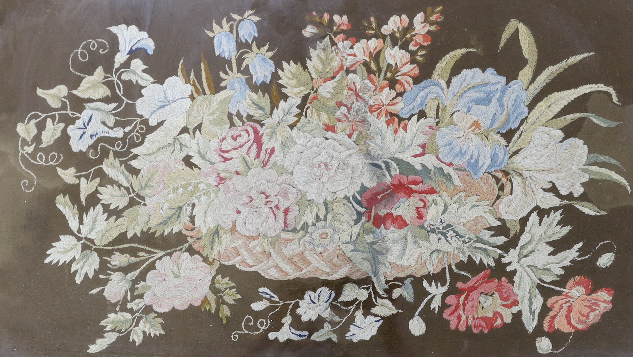 A 19th century framed floral needlework embroidery of a basket of flowers. Worked in multi coloured silks on a felt background, 65cm wide x 38cm high